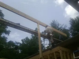 Carpenter setting a ridge beam over a new addition frame — Ice Dam Removal by Roofing Brothers in Lone Oak