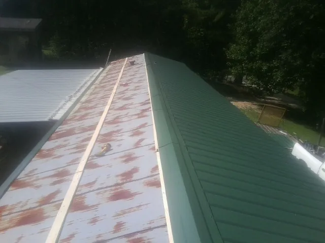 Old rusted panels beside newly installed green metal roofing — Wind Damage Roof Repair by Roofing Brothers in Lone Oak