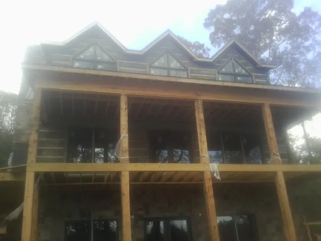 Dormers and porch framing on a large log home under construction — Roof Coating work by our crew in Lone Oak