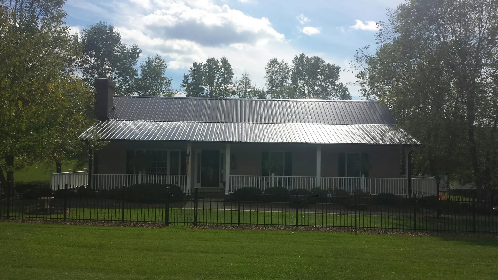 Gray metal roof on a brick ranch with a full width front porch — Gutter Guard Installation work by our crew in Lone Oak