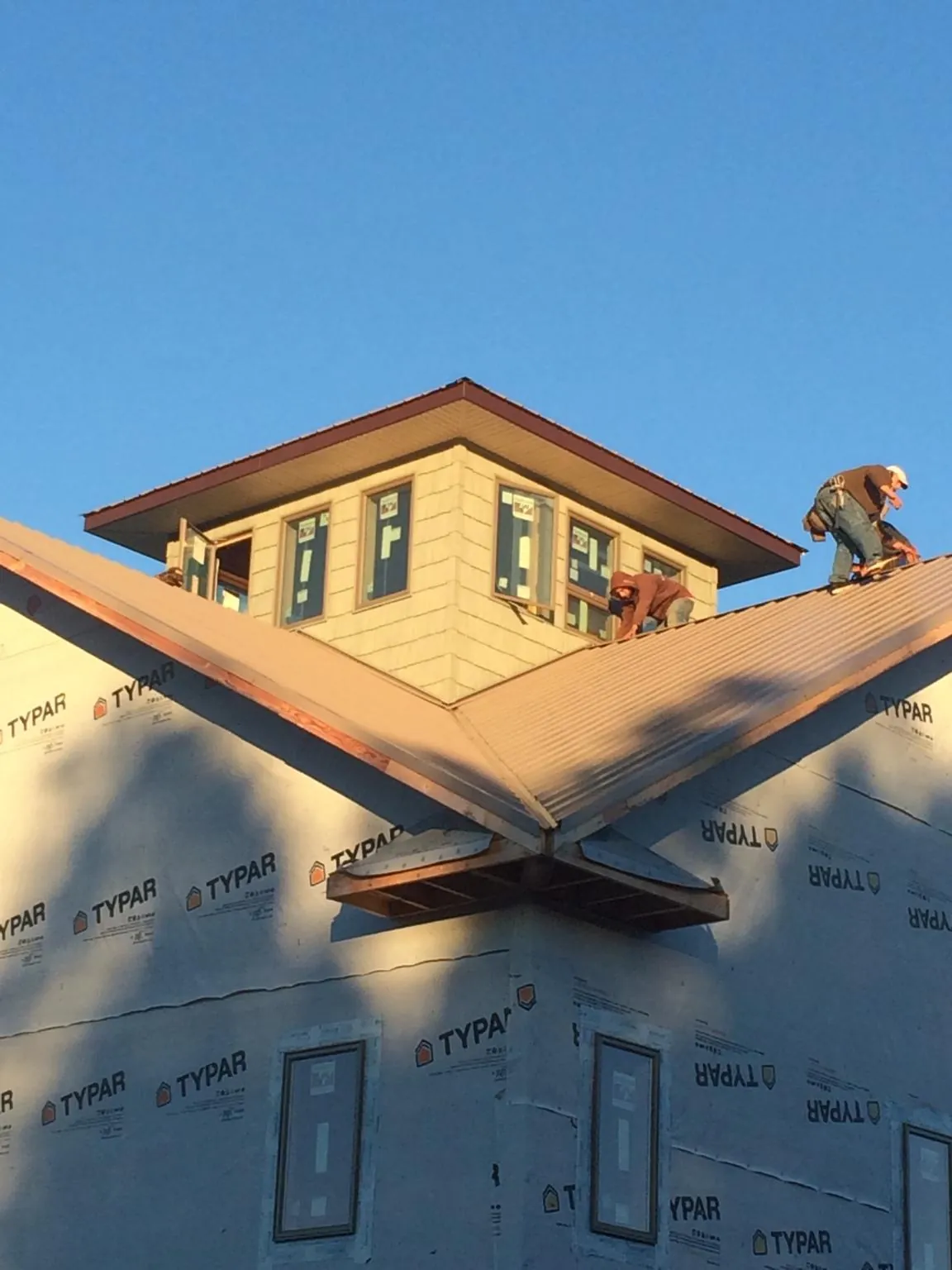 Roofers working around a rooftop cupola on a new metal roof at sunset — Roof Waterproofing in Lone Oak by Roofing Brothers